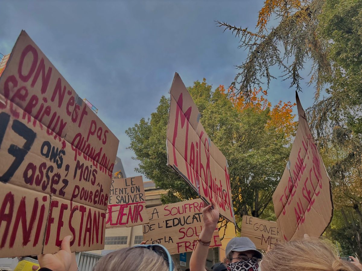 Pancartes en carton levées dans une manifestation, dont « On n'est pas sérieux quand on a 17 ans, mais assez pour être manifestant »