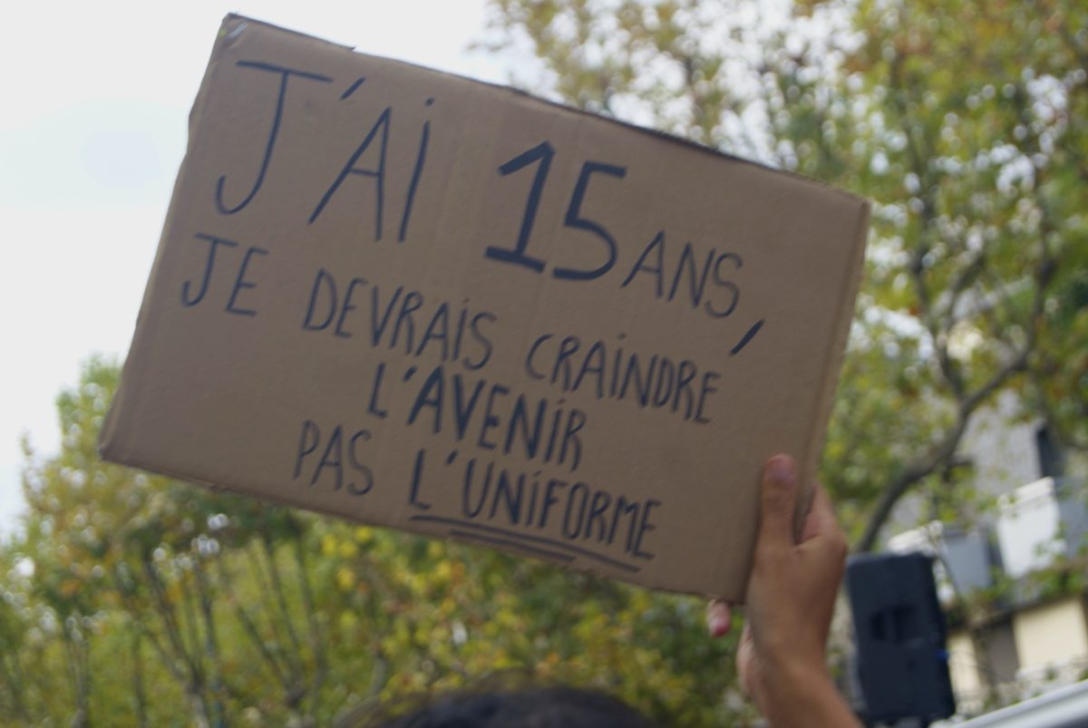 Pancarte en carton levée : « J'ai 15 ans, je devrais craindre l'avenir pas l'uniforme »