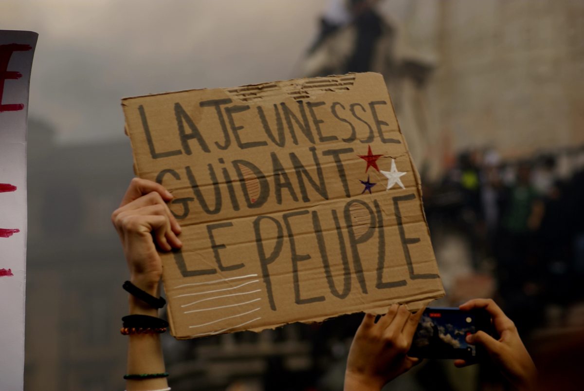 Pancarte en carton « La jeunesse guidant le peuple » tenue à bout de bras dans une manifestation